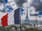 Det franske flagget vaier i vinden foran Eiffeltårnet i Paris