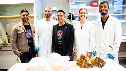 fire menn og en kvinne i en lab, tre har hvite frakker på, to er i vanlige klær