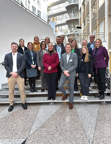 Bilde av en gjeng middelaldrende mennesker i blazer som smiler og ser i kamera.